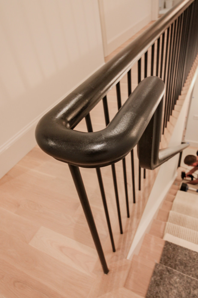 Modelo de escalera en U minimalista grande con escalones de madera, contrahuellas de madera pintada, barandilla de varios materiales y boiserie