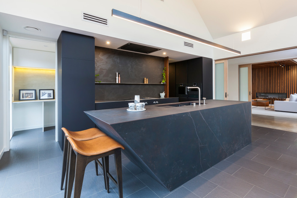 Inspiration for a mid-sized contemporary galley eat-in kitchen in Christchurch with flat-panel cabinets, black cabinets, black splashback, with island, an undermount sink, porcelain splashback, stainless steel appliances, porcelain floors and black floor.