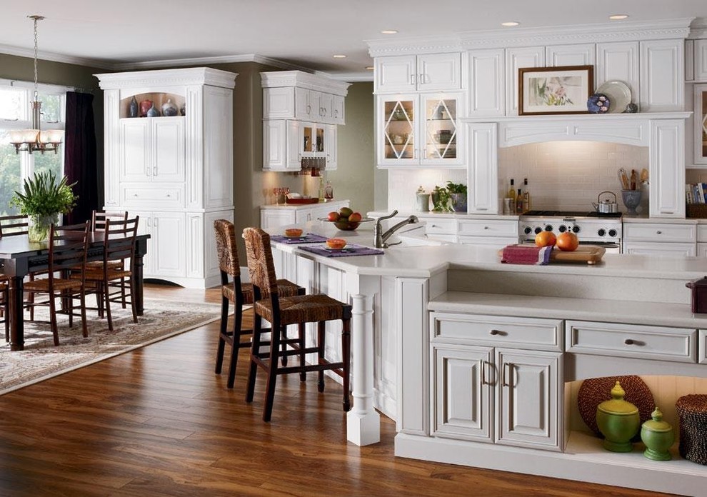 This is an example of a large country eat-in kitchen in Miami with an undermount sink, raised-panel cabinets, white cabinets, stainless steel appliances, medium hardwood floors, with island and brown floor.