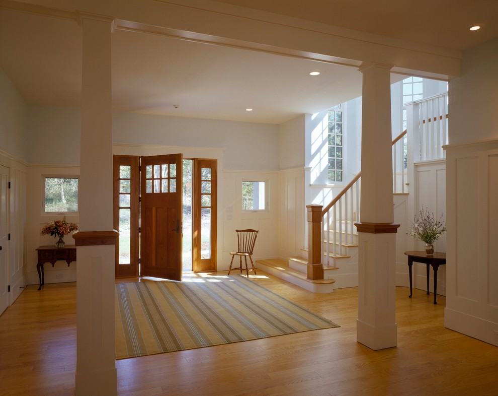 Example of a large transitional light wood floor hallway design with white walls