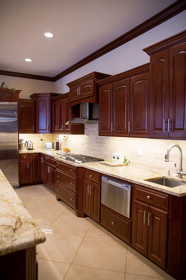 Inspiration for a large modern u-shaped porcelain tile and beige floor open concept kitchen remodel with an undermount sink, raised-panel cabinets, dark wood cabinets, granite countertops, beige backsplash, matchstick tile backsplash, stainless steel appliances, an island and multicolored countertops
