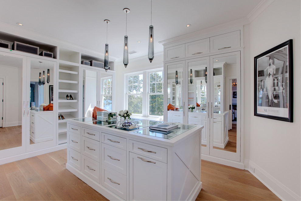 Inspiration for a large beach style women's walk-in wardrobe in Other with white cabinets, light hardwood floors, beige floor and shaker cabinets.