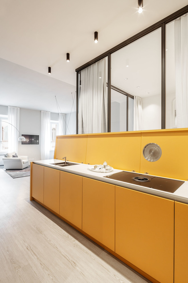 This is an example of a modern single-wall eat-in kitchen in Other with an undermount sink, flat-panel cabinets, yellow cabinets, yellow splashback, light hardwood floors, white benchtop, no island and beige floor.
