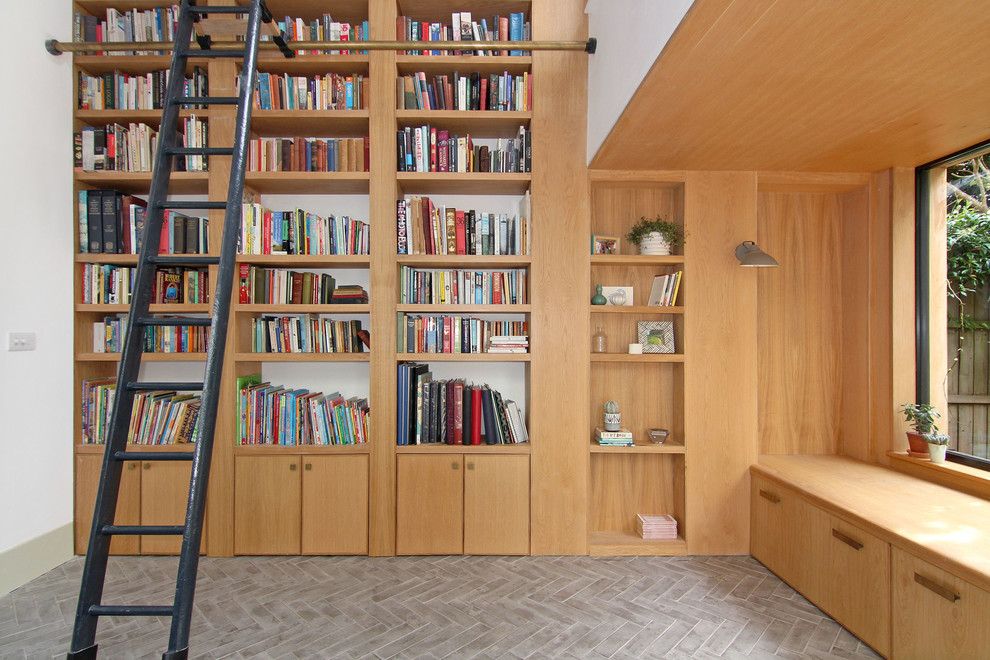 This is an example of a mid-sized modern home office in London with a library, white walls, concrete floors and grey floor.