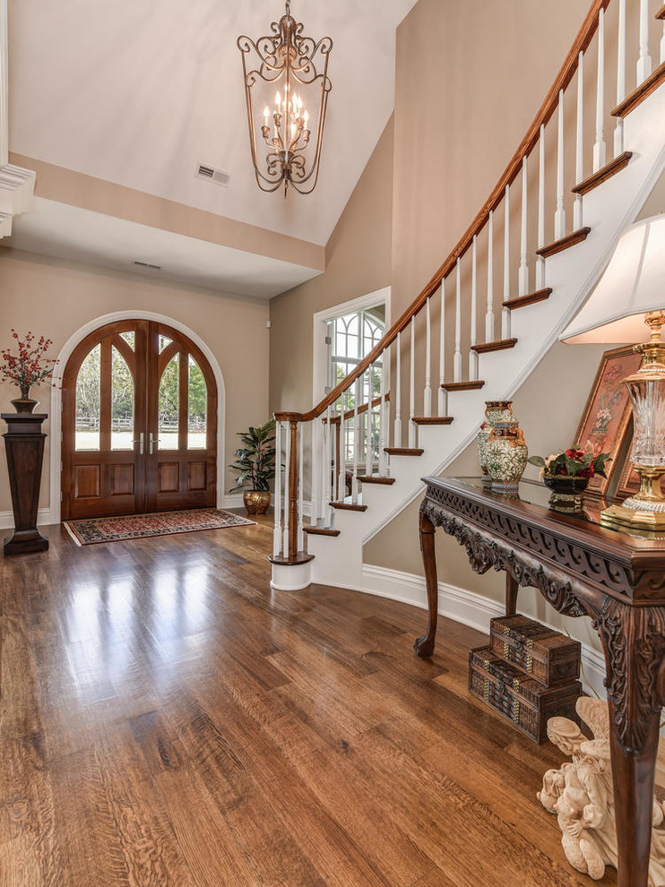 Example of a large transitional medium tone wood floor and brown floor foyer design with beige walls and a medium wood front door