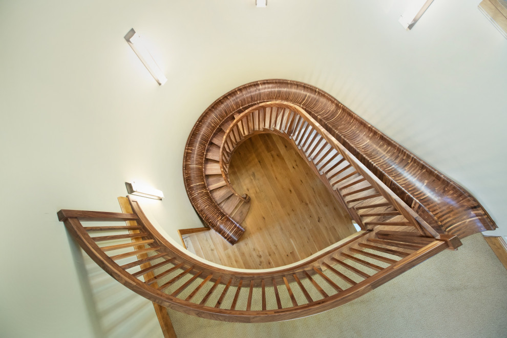 Expansive eclectic wood curved staircase in Sacramento with open risers and wood railing.