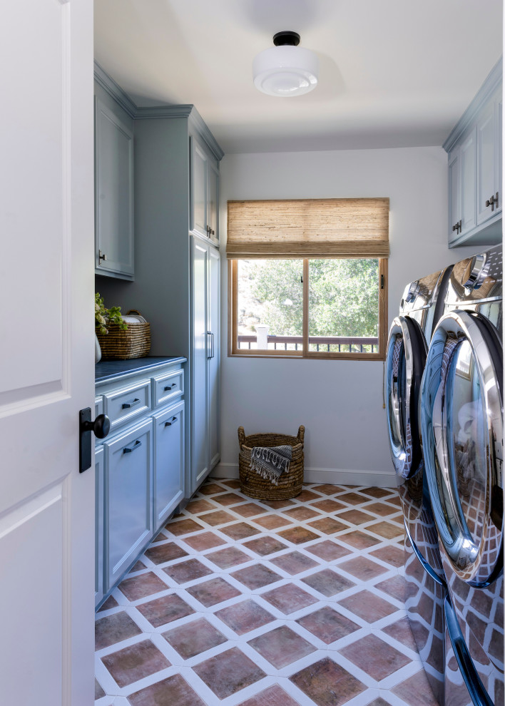 Inspiration for a medium sized country galley laundry cupboard in San Francisco with a built-in sink, raised-panel cabinets, blue cabinets, marble worktops, grey splashback, marble splashback, white walls, porcelain flooring, a side by side washer and dryer and grey worktops.