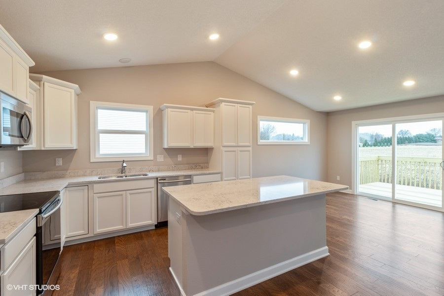 Kitchen - mid-sized transitional single-wall medium tone wood floor and brown floor kitchen idea with an undermount sink, shaker cabinets, white cabinets, quartz countertops, white backsplash, quartz backsplash, stainless steel appliances, an island and white countertops
