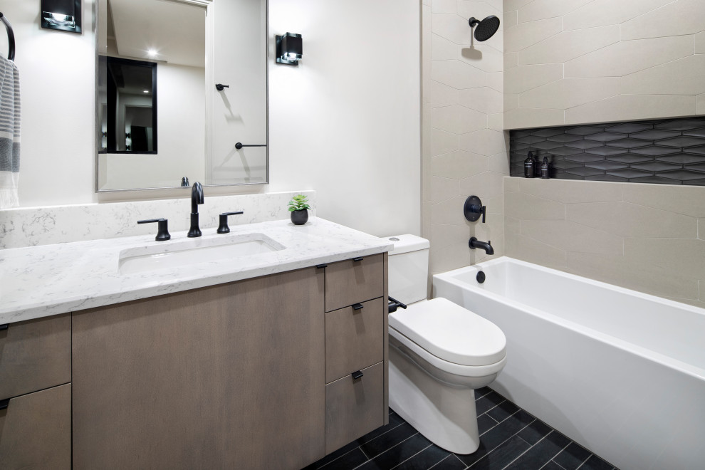 This is an example of a mid-sized modern kids bathroom in Austin with flat-panel cabinets, light wood cabinets, an alcove tub, a shower/bathtub combo, a one-piece toilet, beige tile, ceramic tile, white walls, ceramic floors, an undermount sink, engineered quartz benchtops, black floor, a shower curtain, white benchtops, a niche, a single vanity and a floating vanity.