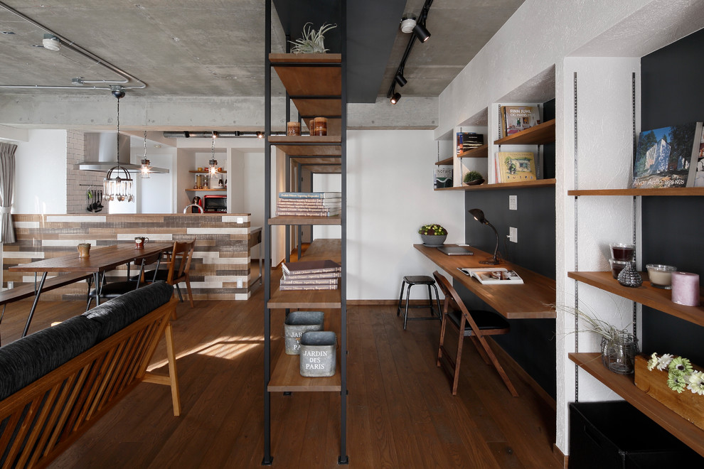 Industrial home office in Tokyo with multi-coloured walls, dark hardwood floors, a built-in desk and brown floor.