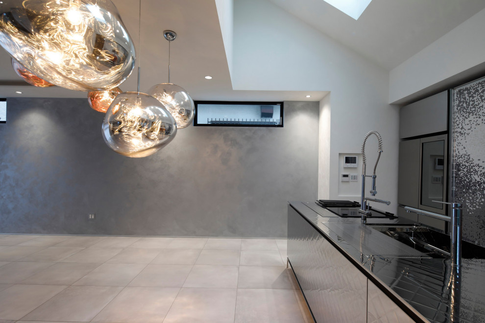 Example of an urban single-wall ceramic tile, gray floor and vaulted ceiling open concept kitchen design in Tokyo with a single-bowl sink, glass-front cabinets, stainless steel cabinets, stainless steel countertops, metallic backsplash, metal backsplash, black appliances and an island