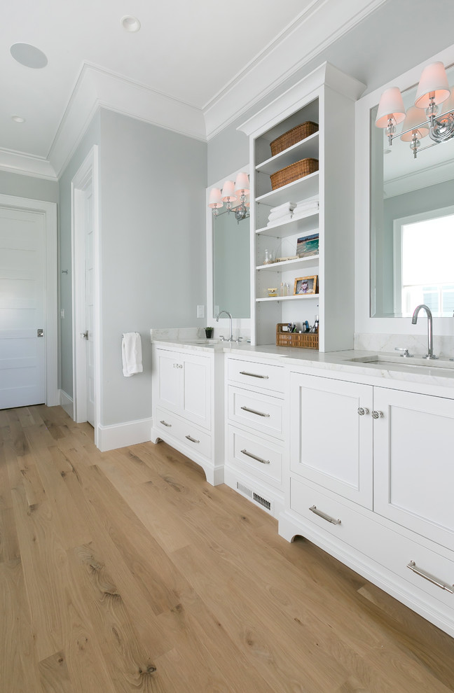This is an example of a mid-sized beach style master bathroom in Charleston with grey walls, light hardwood floors, a hinged shower door, an undermount sink and beige floor.
