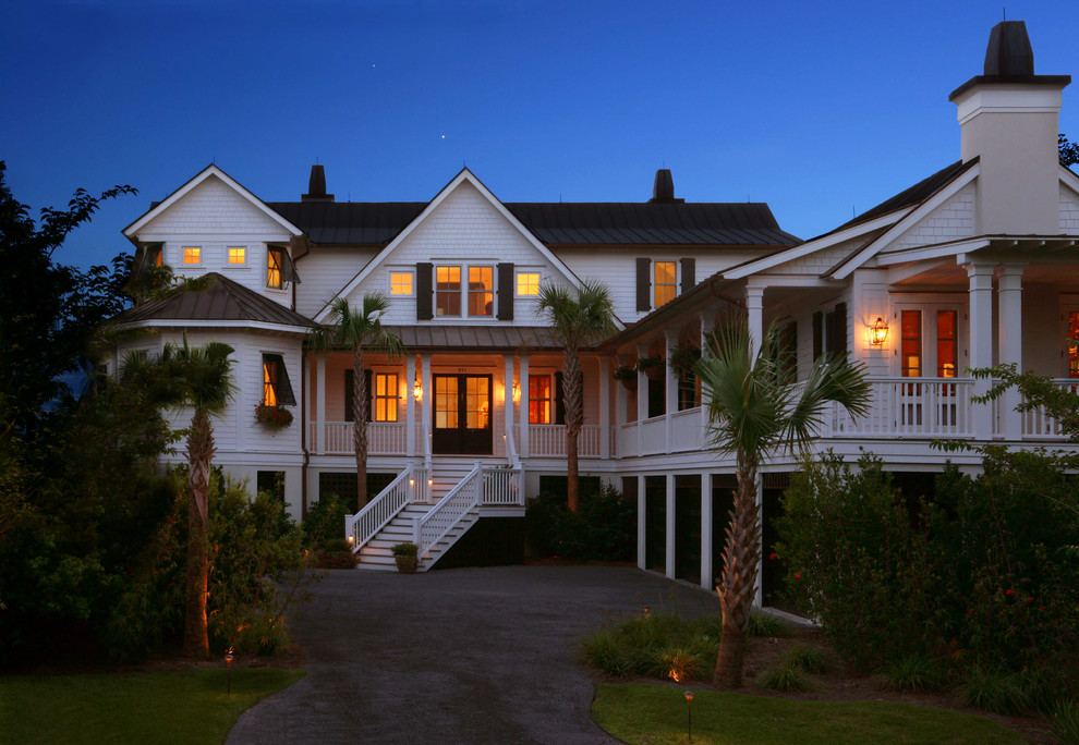 This is an example of a beach style two-storey white house exterior in Charleston with wood siding and a metal roof.