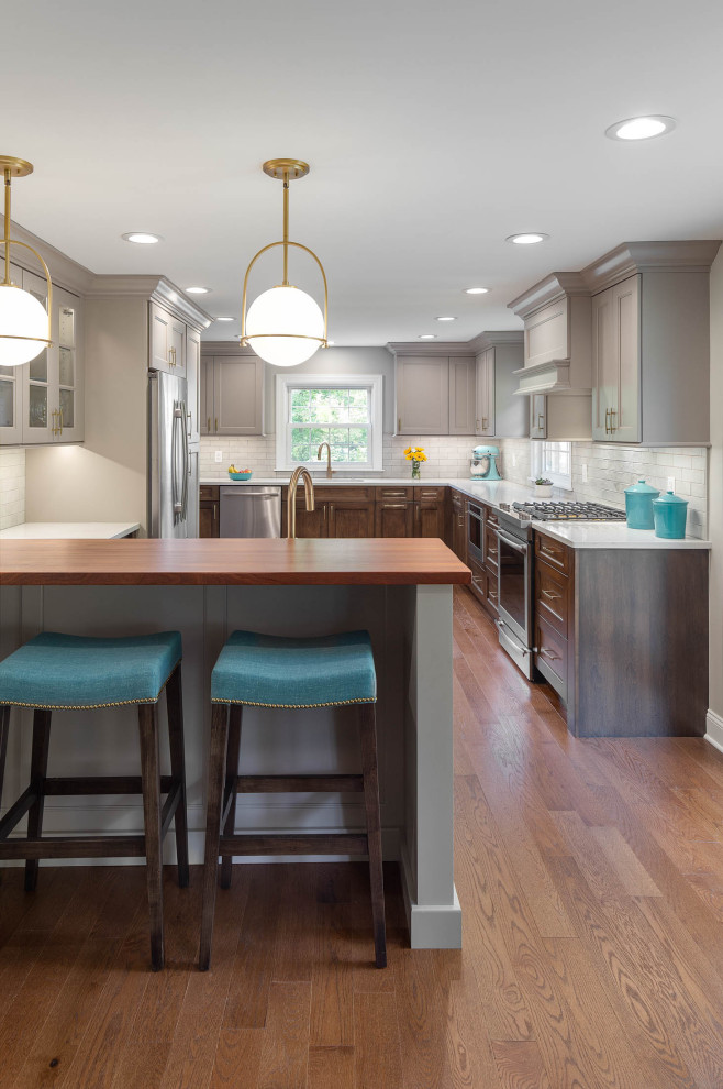 Inspiration for a transitional l-shaped eat-in kitchen remodel with recessed-panel cabinets, quartz countertops, white backsplash, subway tile backsplash, stainless steel appliances, a peninsula and white countertops