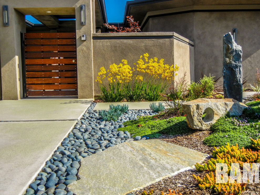Photo of a mid-sized traditional front yard full sun xeriscape for summer in Los Angeles with concrete pavers.