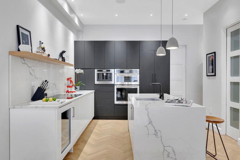 Trendy light wood floor and beige floor kitchen photo in New York with a single-bowl sink, flat-panel cabinets, white backsplash, stainless steel appliances, an island and white countertops