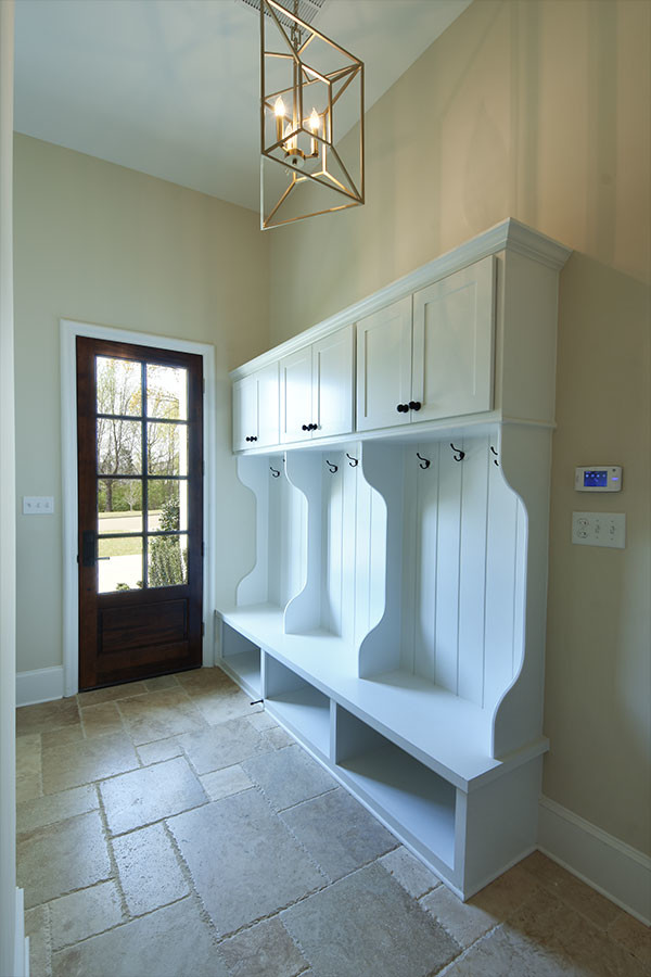 Mid-sized transitional limestone floor and beige floor mudroom photo with beige walls and a dark wood front door