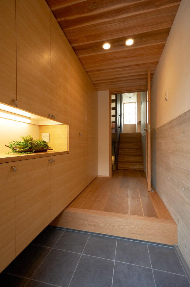 This is an example of a modern entryway in Osaka with a single front door, beige walls, porcelain floors, a medium wood front door and grey floor.
