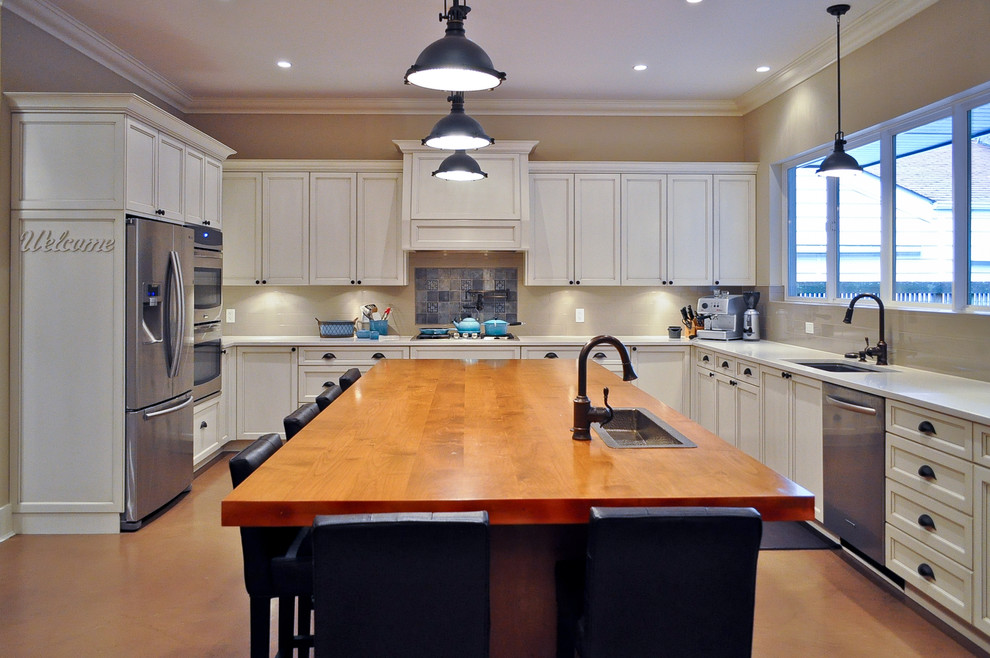 Inspiration for a large traditional u-shaped kitchen in Vancouver with an undermount sink, recessed-panel cabinets, white cabinets, wood benchtops, stainless steel appliances, concrete floors, with island and brown floor.