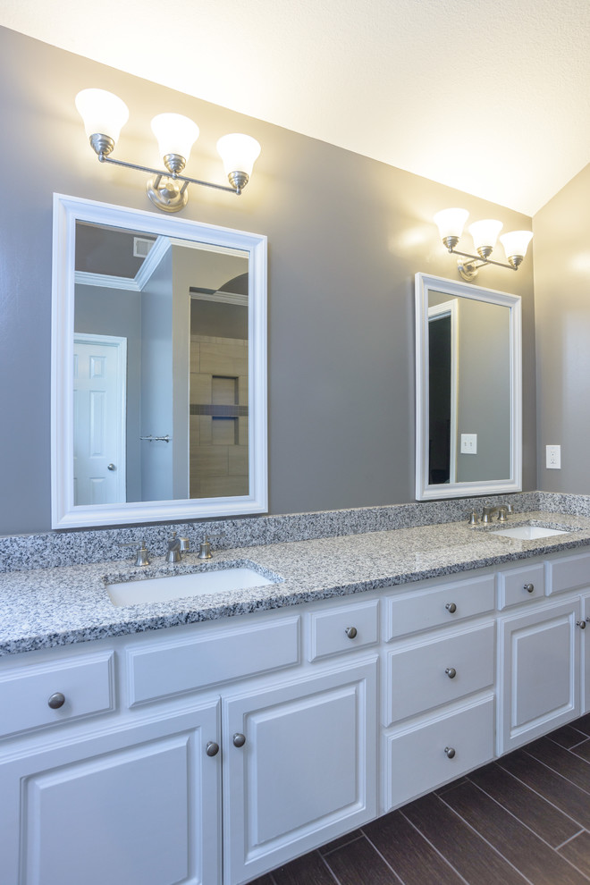 This is an example of a mid-sized transitional master bathroom in Kansas City with raised-panel cabinets, white cabinets, grey walls, porcelain floors, an undermount sink, brown floor, a freestanding tub, an alcove shower, gray tile, porcelain tile, terrazzo benchtops and an open shower.