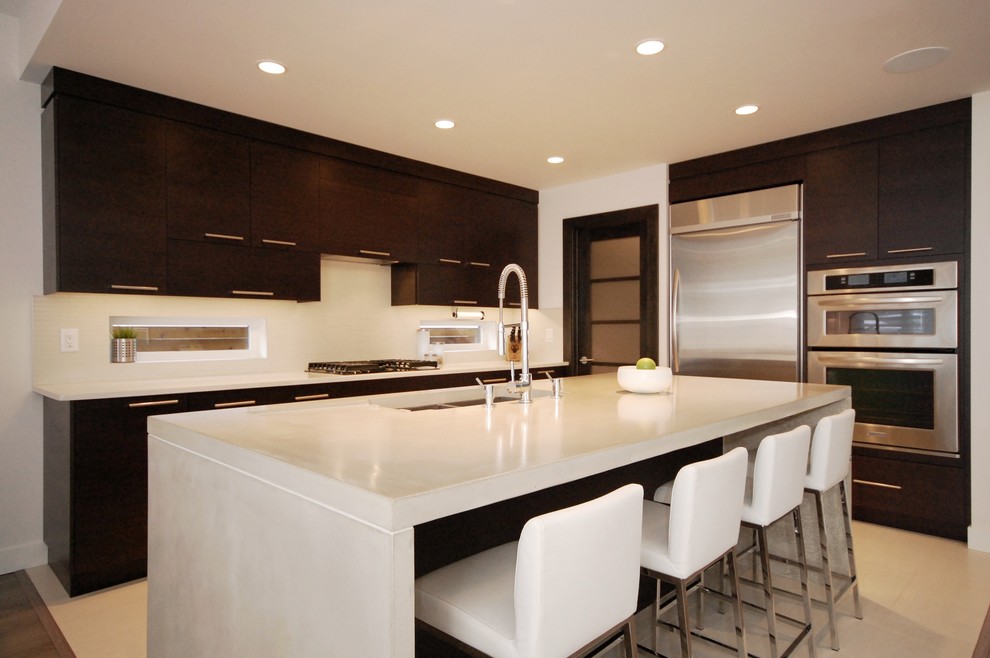 Inspiration for a large modern l-shaped eat-in kitchen in Edmonton with an undermount sink, flat-panel cabinets, dark wood cabinets, concrete benchtops, white splashback, subway tile splashback, stainless steel appliances, ceramic floors and with island.