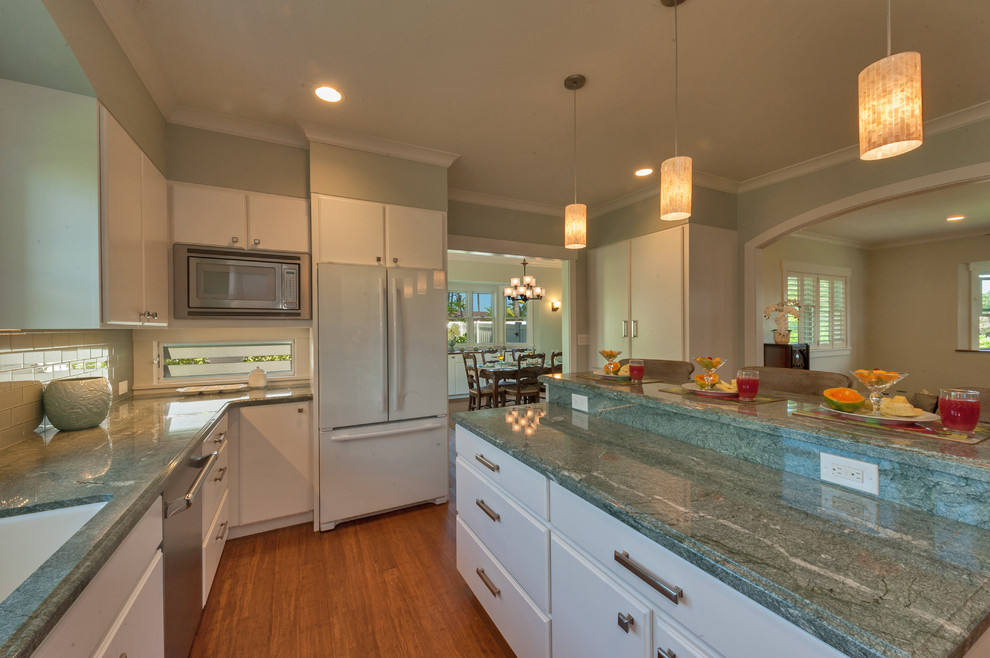 This is an example of an arts and crafts separate kitchen in Hawaii with a double-bowl sink, white cabinets, granite benchtops, glass tile splashback, white appliances, bamboo floors and with island.