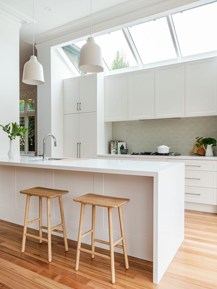 Mid-sized contemporary galley eat-in kitchen in Melbourne with shaker cabinets, white cabinets, quartzite benchtops, ceramic splashback, light hardwood floors, white benchtop, an undermount sink, panelled appliances, a peninsula, beige floor and vaulted.