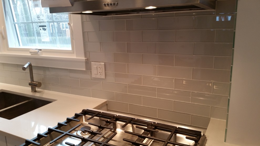 Mid-sized minimalist galley dark wood floor eat-in kitchen photo with an undermount sink, recessed-panel cabinets, white cabinets, granite countertops, white backsplash, glass tile backsplash, stainless steel appliances and a peninsula