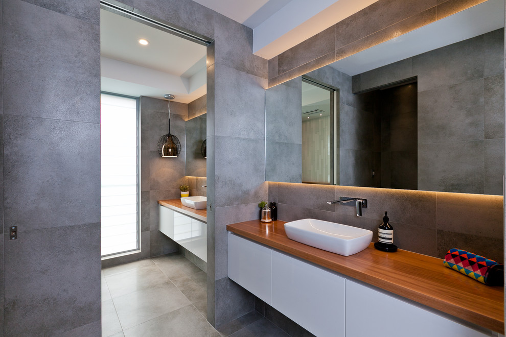 Design ideas for a contemporary bathroom in Perth with flat-panel cabinets, white cabinets, gray tile, a vessel sink and wood benchtops.