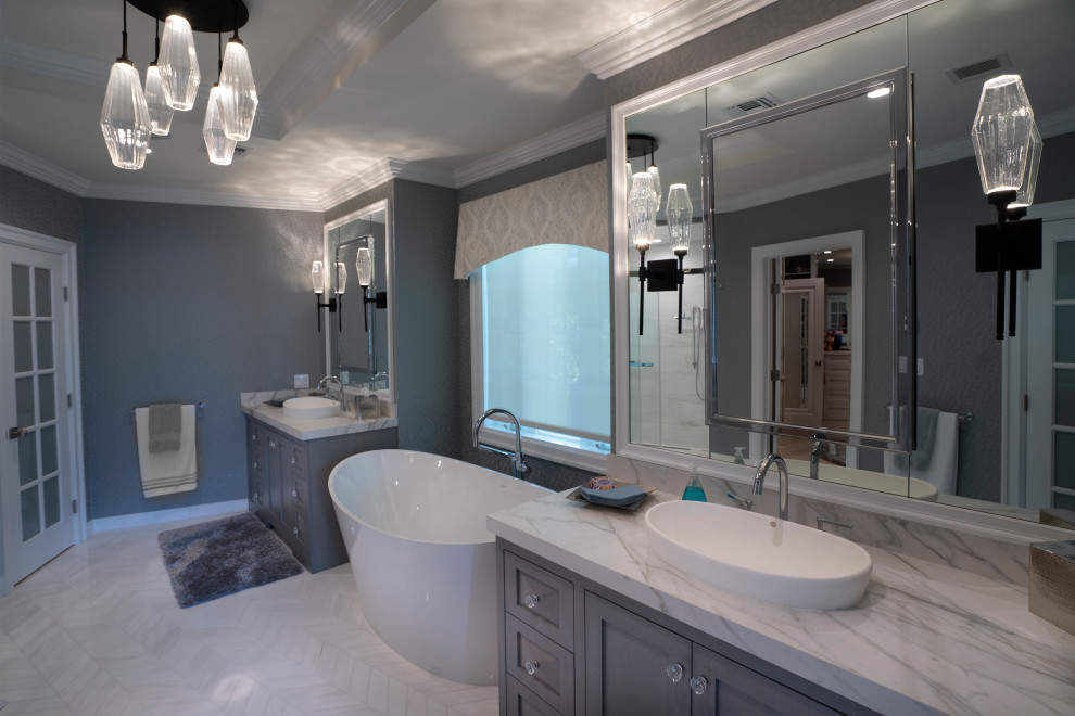 Inspiration for a mid-sized transitional master bathroom in New York with grey cabinets, a freestanding tub, grey walls, porcelain floors, marble benchtops, white floor and white benchtops.