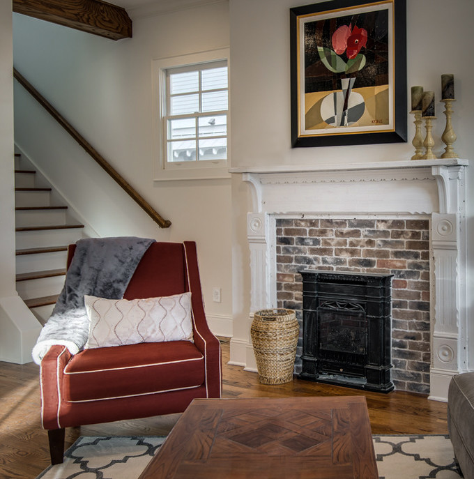 This is an example of a country open concept living room in Nashville with white walls, a standard fireplace and a brick fireplace surround.