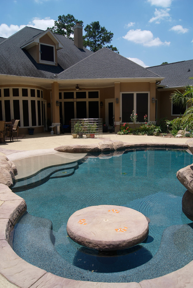 Design ideas for a mid-sized tropical backyard custom-shaped natural pool in Houston with a water slide and stamped concrete.