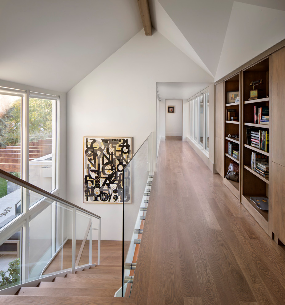 Immagine di un ingresso o corridoio minimal con pavimento in legno massello medio, pareti bianche e pavimento marrone