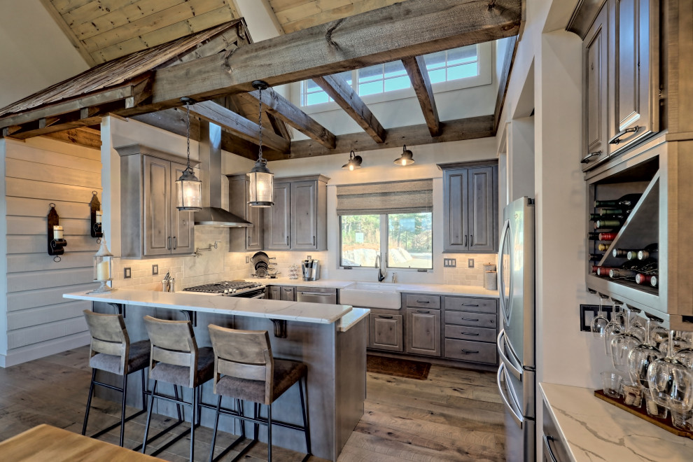 This is an example of a small country u-shaped open plan kitchen in Atlanta with a farmhouse sink, raised-panel cabinets, quartz benchtops, white splashback, travertine splashback, stainless steel appliances, a peninsula, brown floor, white benchtop, grey cabinets and medium hardwood floors.