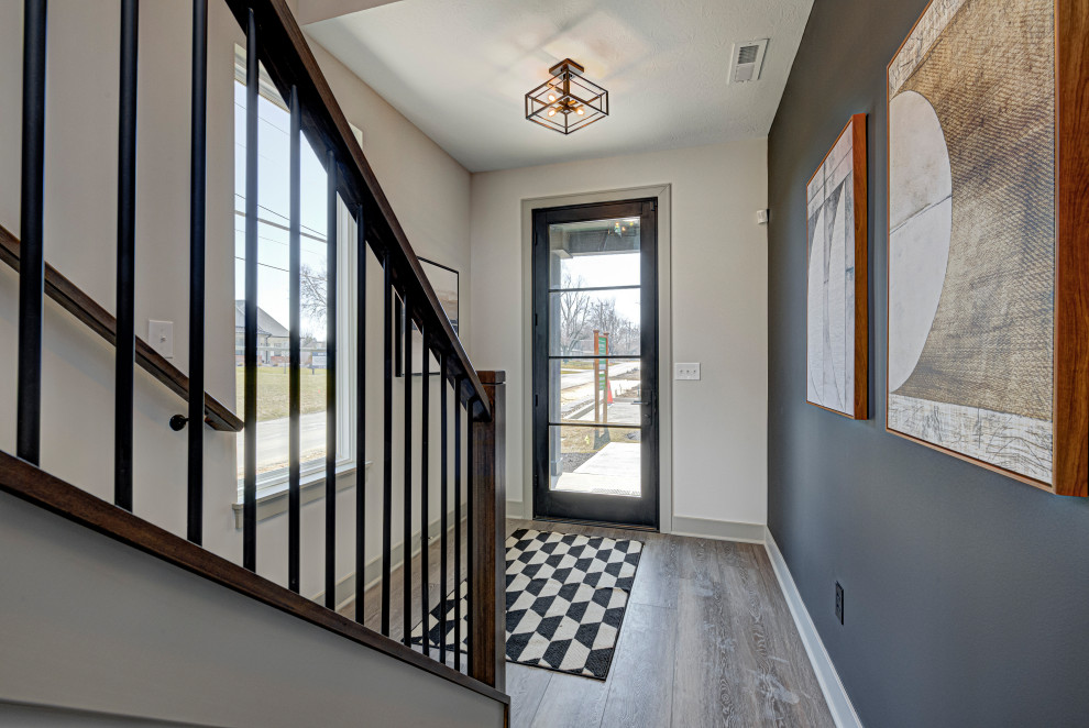This is an example of a mid-sized contemporary front door in Indianapolis with multi-coloured walls, a single front door, a glass front door, brown floor and medium hardwood floors.