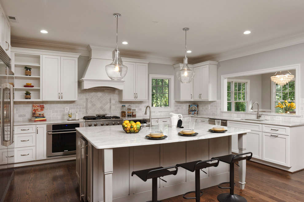 This is an example of a large transitional u-shaped open plan kitchen in DC Metro with a single-bowl sink, flat-panel cabinets, white cabinets, grey splashback, stone tile splashback, stainless steel appliances, dark hardwood floors, with island and marble benchtops.