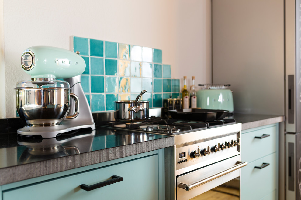 Example of a trendy galley open concept kitchen design in Cologne with a drop-in sink, turquoise cabinets, white backsplash, mosaic tile backsplash and an island