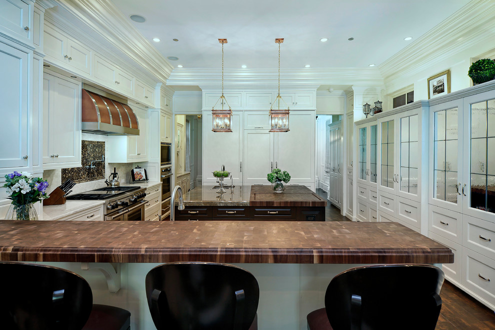 Photo of an expansive traditional u-shaped eat-in kitchen in Chicago with an undermount sink, stainless steel appliances, dark hardwood floors, with island, shaker cabinets, white cabinets, marble benchtops, white splashback and stone slab splashback.