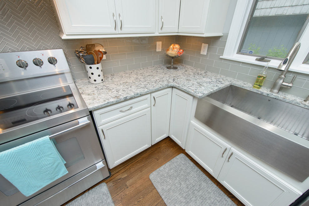 Kitchen - large transitional l-shaped dark wood floor and brown floor kitchen idea in Baltimore with a farmhouse sink, recessed-panel cabinets, white cabinets, quartz countertops, gray backsplash, subway tile backsplash, stainless steel appliances and an island