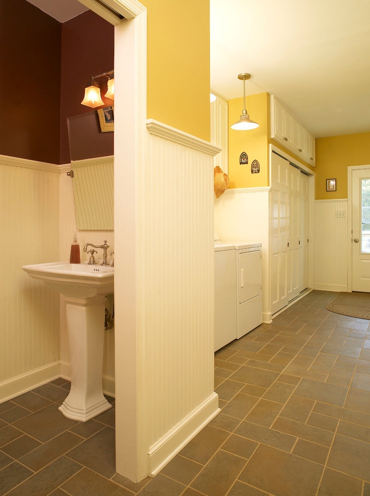 Design ideas for a large country single-wall utility room in Philadelphia with raised-panel cabinets, white cabinets, yellow walls, slate floors, a side-by-side washer and dryer and grey floor.