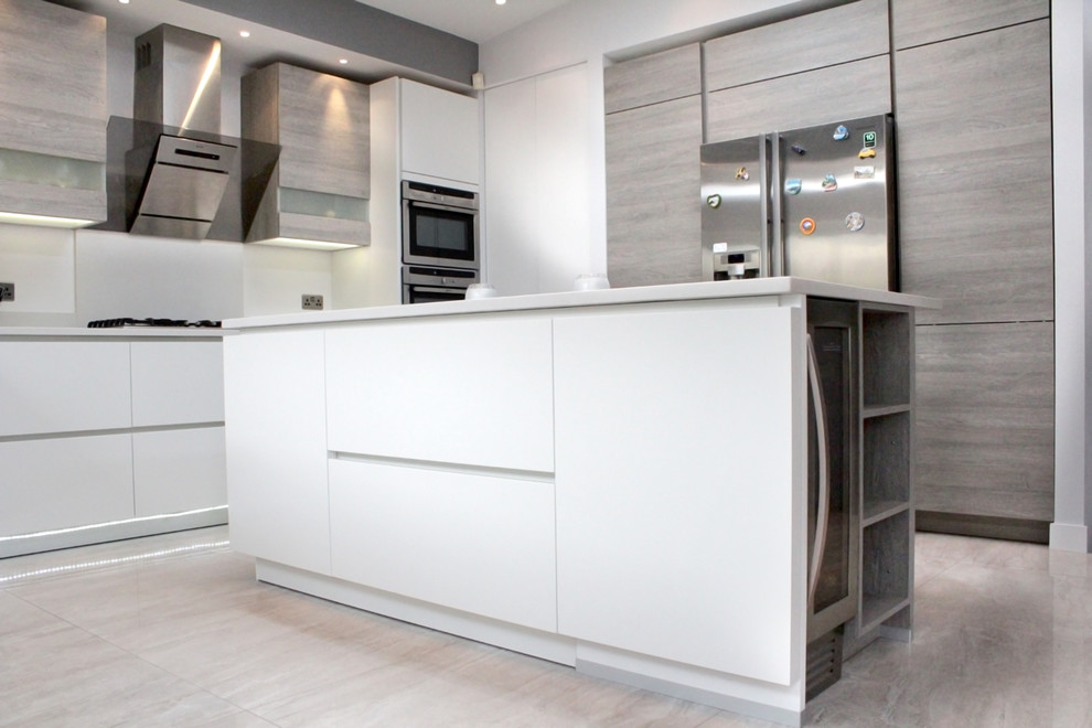 Small l-shaped eat-in kitchen in London with an integrated sink, flat-panel cabinets, white cabinets, laminate benchtops, white splashback, porcelain splashback, stainless steel appliances, porcelain floors and with island.