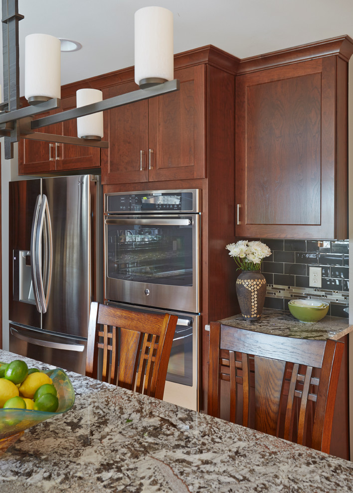 Open concept kitchen - large transitional l-shaped light wood floor open concept kitchen idea in Milwaukee with an undermount sink, shaker cabinets, dark wood cabinets, granite countertops, gray backsplash, subway tile backsplash, stainless steel appliances and an island