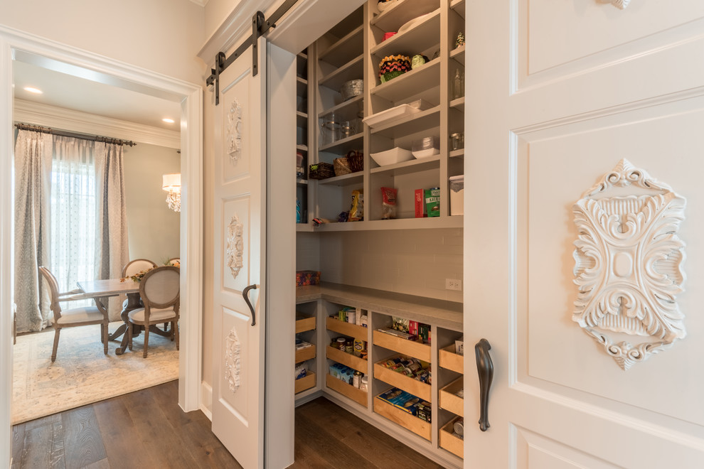 Photo of a large traditional l-shaped kitchen pantry in Houston with open cabinets, grey cabinets, dark hardwood floors and brown floor.