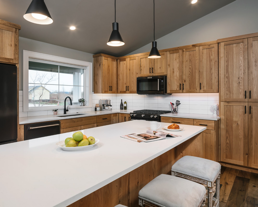 Kitchen - mid-sized transitional l-shaped medium tone wood floor kitchen idea with an undermount sink, white backsplash, porcelain backsplash, black appliances, white countertops, shaker cabinets and an island