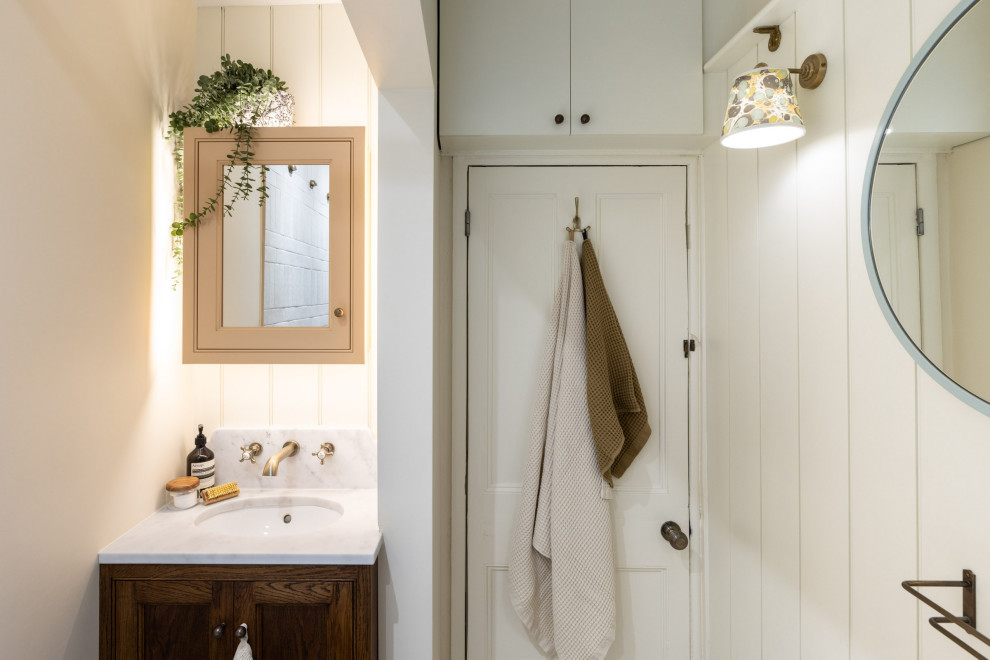 Small farmhouse cream and black family bathroom in Kent with beaded cabinets, dark wood cabinets, a built-in bath, a shower/bath combination, a two-piece toilet, ceramic tiles, white walls, solid surface worktops, multi-coloured floors, a shower curtain, feature lighting, a single sink, a built in vanity unit and tongue and groove walls.