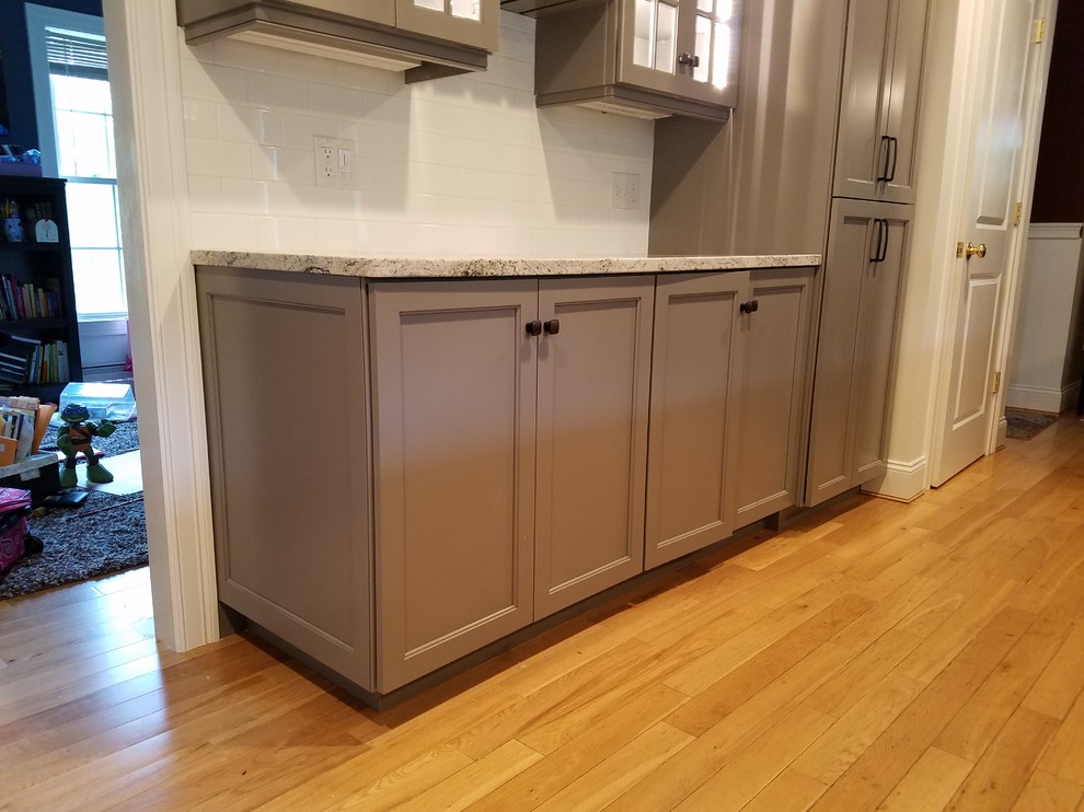 Mid-sized transitional galley light wood floor and brown floor eat-in kitchen photo with a farmhouse sink, recessed-panel cabinets, gray cabinets, wood countertops, white backsplash, subway tile backsplash, stainless steel appliances and an island
