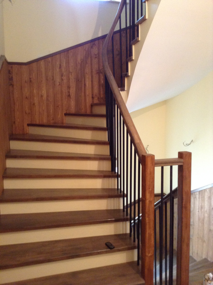 Réalisation d'un escalier courbe tradition de taille moyenne avec des marches en bois, des contremarches en bois, un garde-corps en métal et du papier peint.