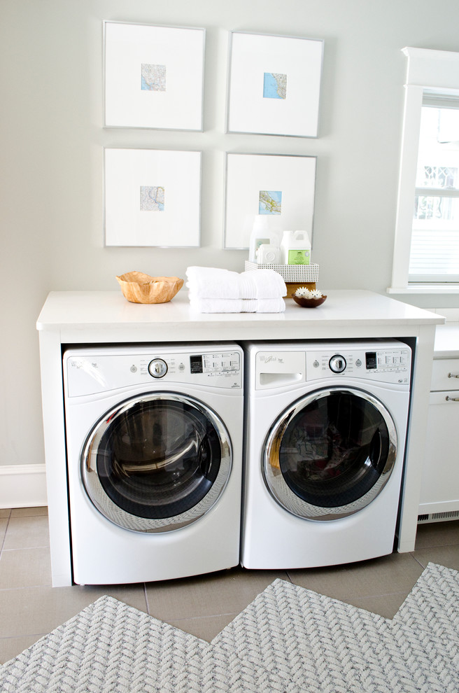 Photo of a small transitional single-wall laundry room in Other with white cabinets, white walls, ceramic floors, a side-by-side washer and dryer and white benchtop.
