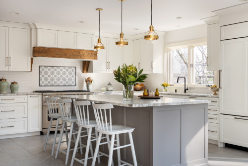 Bright kitchen with white shaker RTA cabinets, gray island, marble-look countertop, brass pendants, and a rustic wood-beam range hood.