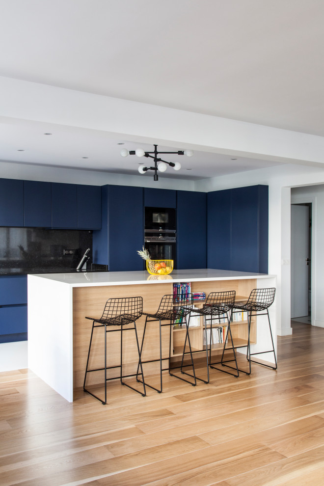 Inspiration for a large contemporary single-wall open plan kitchen in Other with with island, a double-bowl sink, blue cabinets, quartzite benchtops, black splashback, black appliances, ceramic floors, white floor and white benchtop.